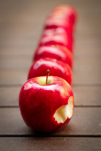 row of apples, one bitten